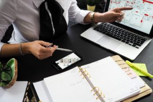 person holding gray pen sitting near laptop