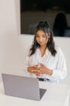 a woman in white dress shirt sitting in front of a laptop