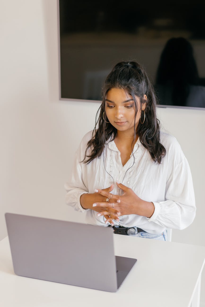 a woman in white dress shirt sitting in front of a laptop